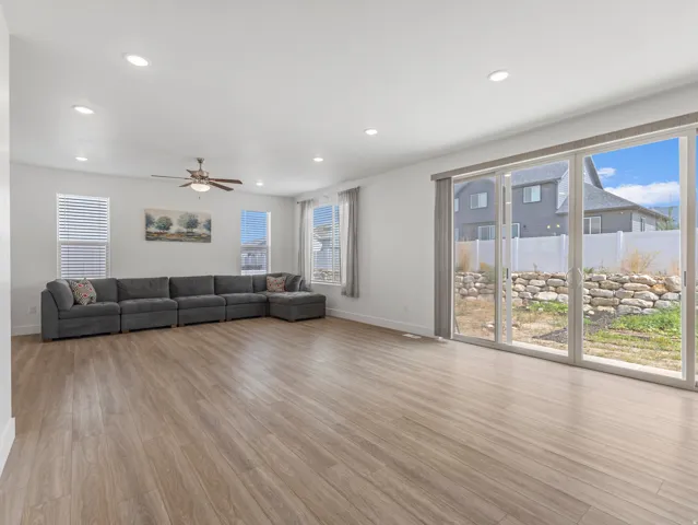 Spacious living area featuring wood-finish flooring, recessed lighting, and a ceiling fan