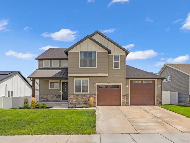 Two-story residence featuring a covered entry, two-car garage, and stone accents