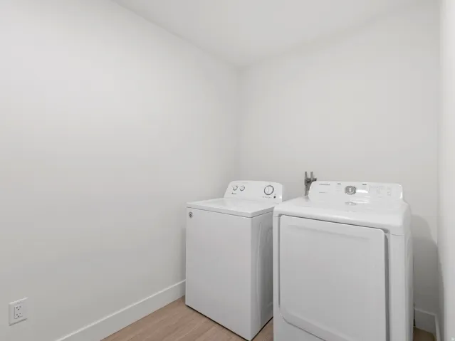 Laundry area with wood-finish flooring and white walls