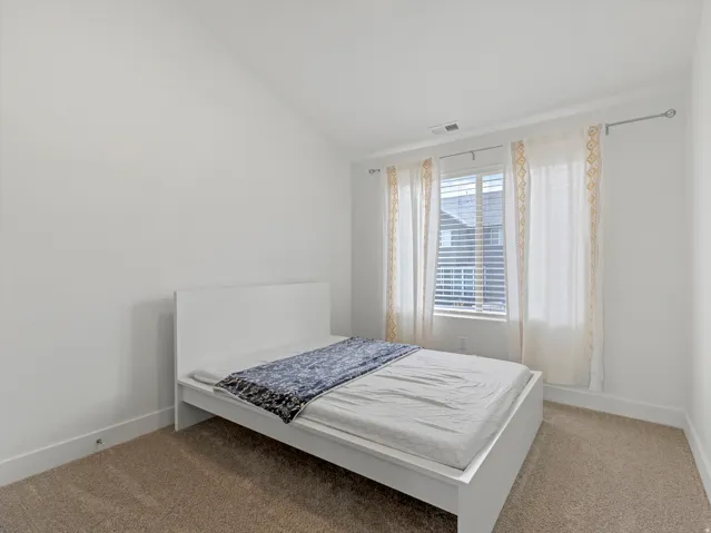Vaulted ceiling, carpeted flooring, window with blinds, and white walls