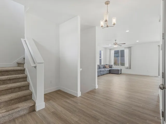 Open-concept living area with wood-finish flooring, ceiling fan, and recessed lighting