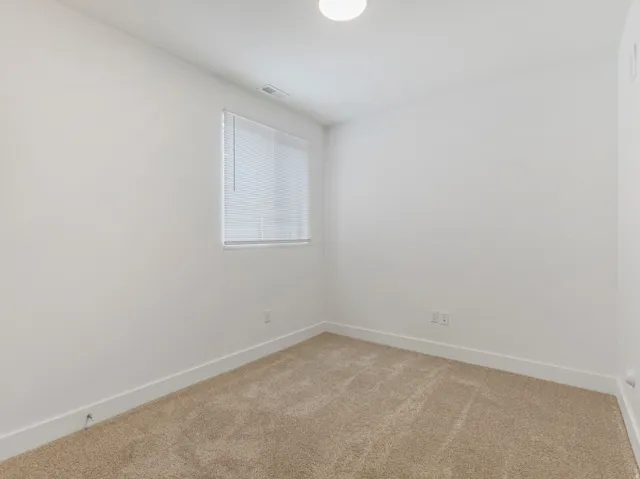 Carpeted flooring, white walls, and a window with horizontal blinds