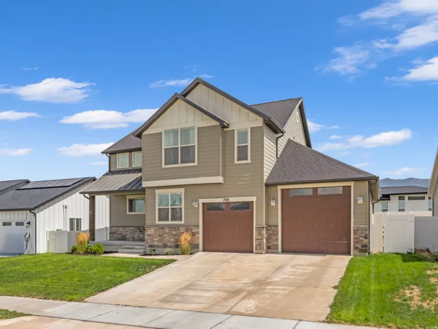 Two-story exterior with a gabled roofline, stone accents, dual garage doors, and a covered porch entry