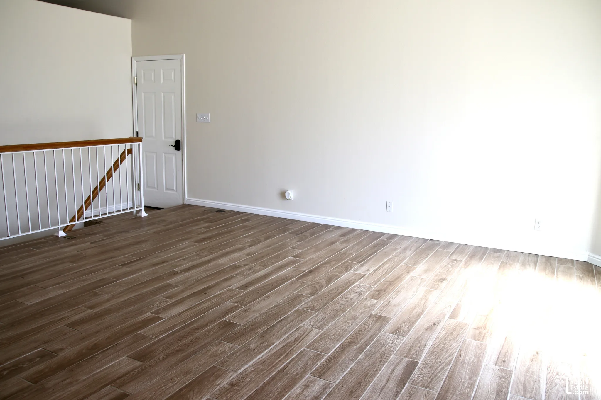 Great room, neutral wall paint, white trim, and a contemporary white railing with a wood-finish handrail