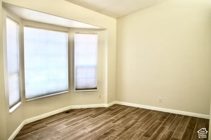 Bay window with three large windows, neutral window treatments, vaulted ceilings, and tile