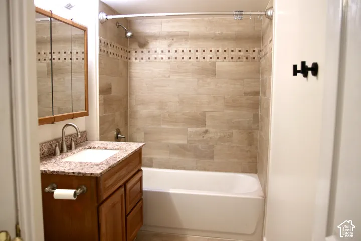 Updated Bathroom featuring a wood-finish vanity with granite countertop, integrated sink, and brushed nickel faucet