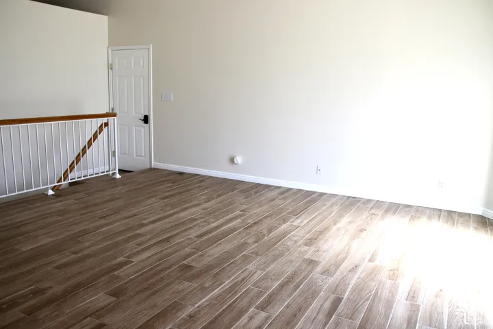 Great room, neutral wall paint, white trim, and a contemporary white railing with a wood-finish handrail