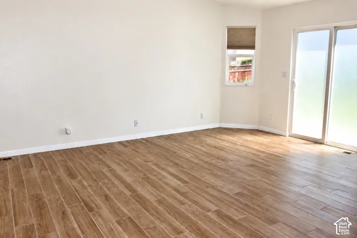 Tile flooring, white wall finishes, a single window with a roller shade, and sliding glass doors