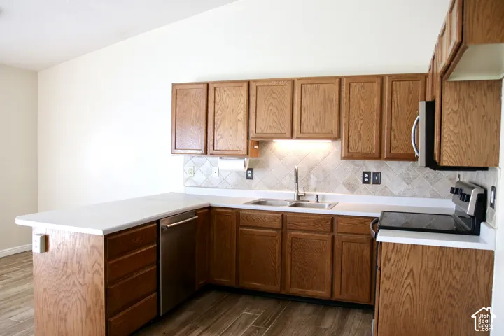Kitchen featuring wood-finish cabinetry, light countertops, stainless steel appliances, a backsplash, and Tile floor