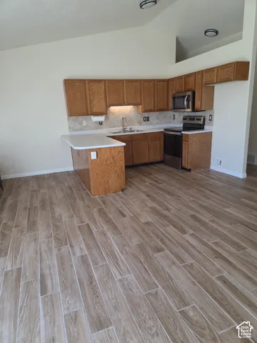 Kitchen featuring wood cabinetry, stainless steel appliances, white countertops, and a subway tile backsplash