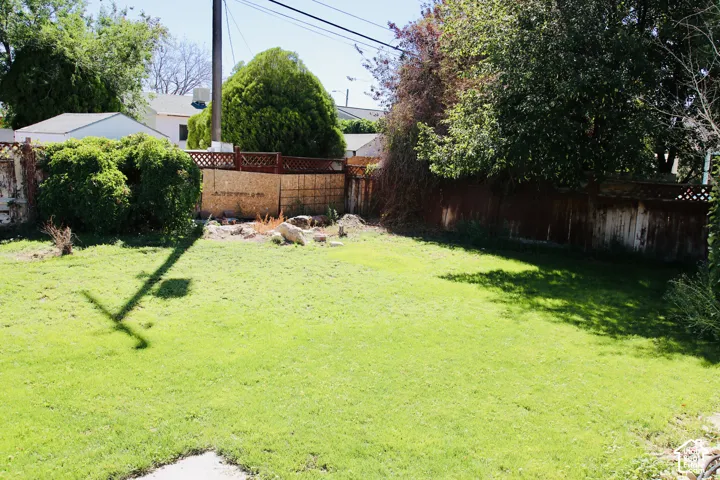Expansive grassy lawn with mature trees and a wood fence
