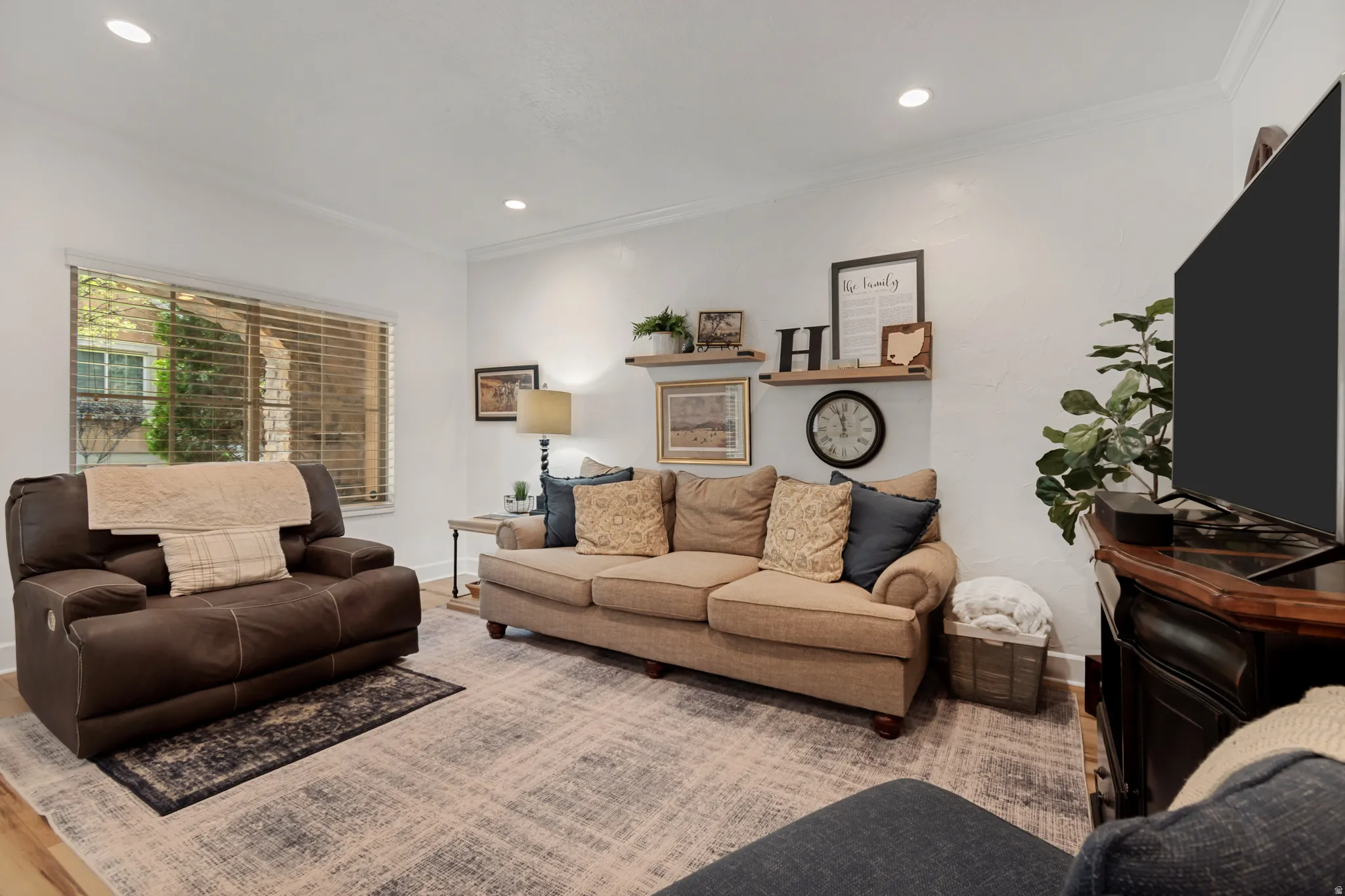 Bright and spacious living room featuring recessed ceiling lighting, LVP flooring, and neutral wall finishes
