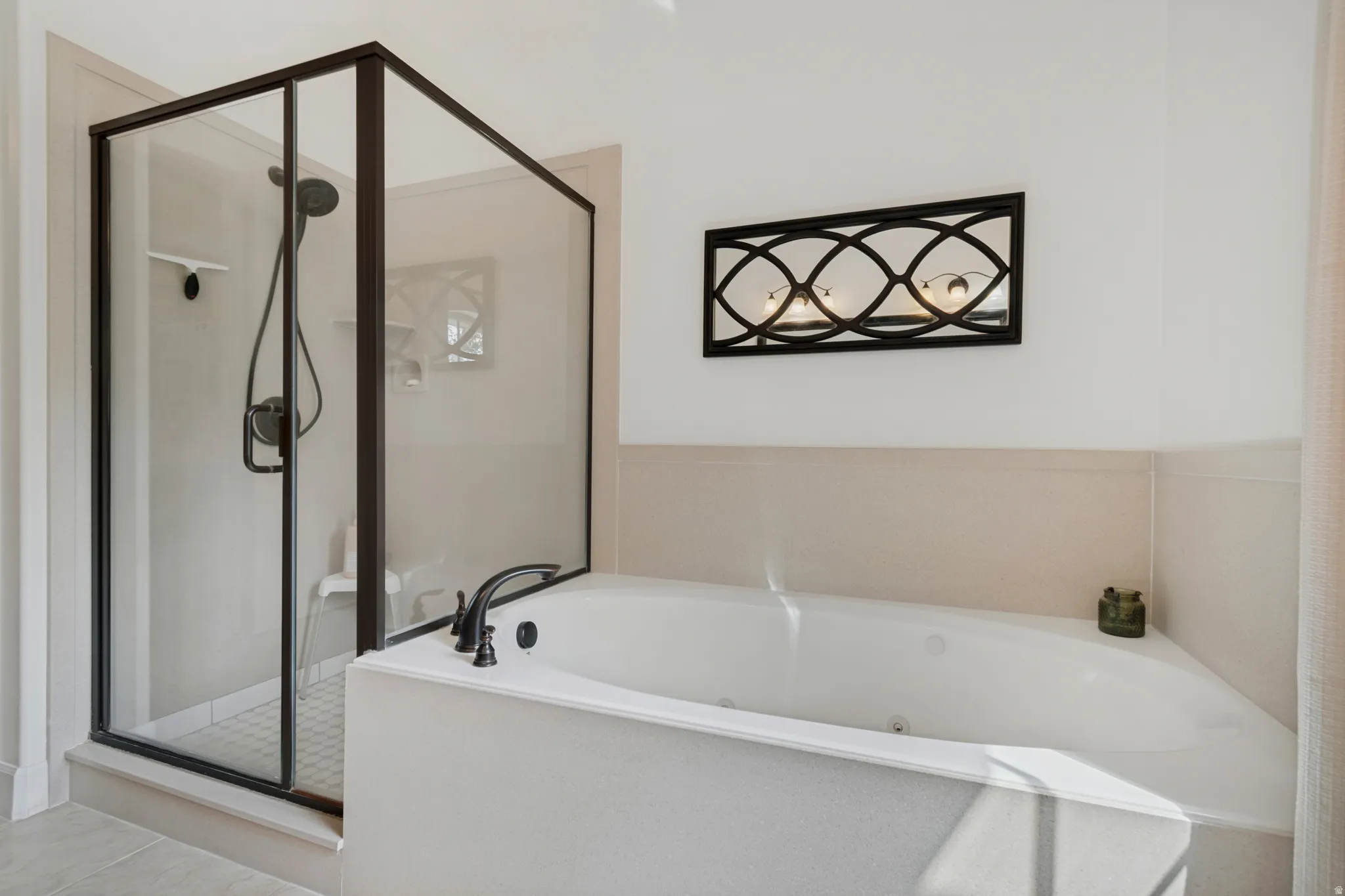 Walk-in shower with dark-framed glass enclosure, built-in soaking tub, and decorative wall sconce