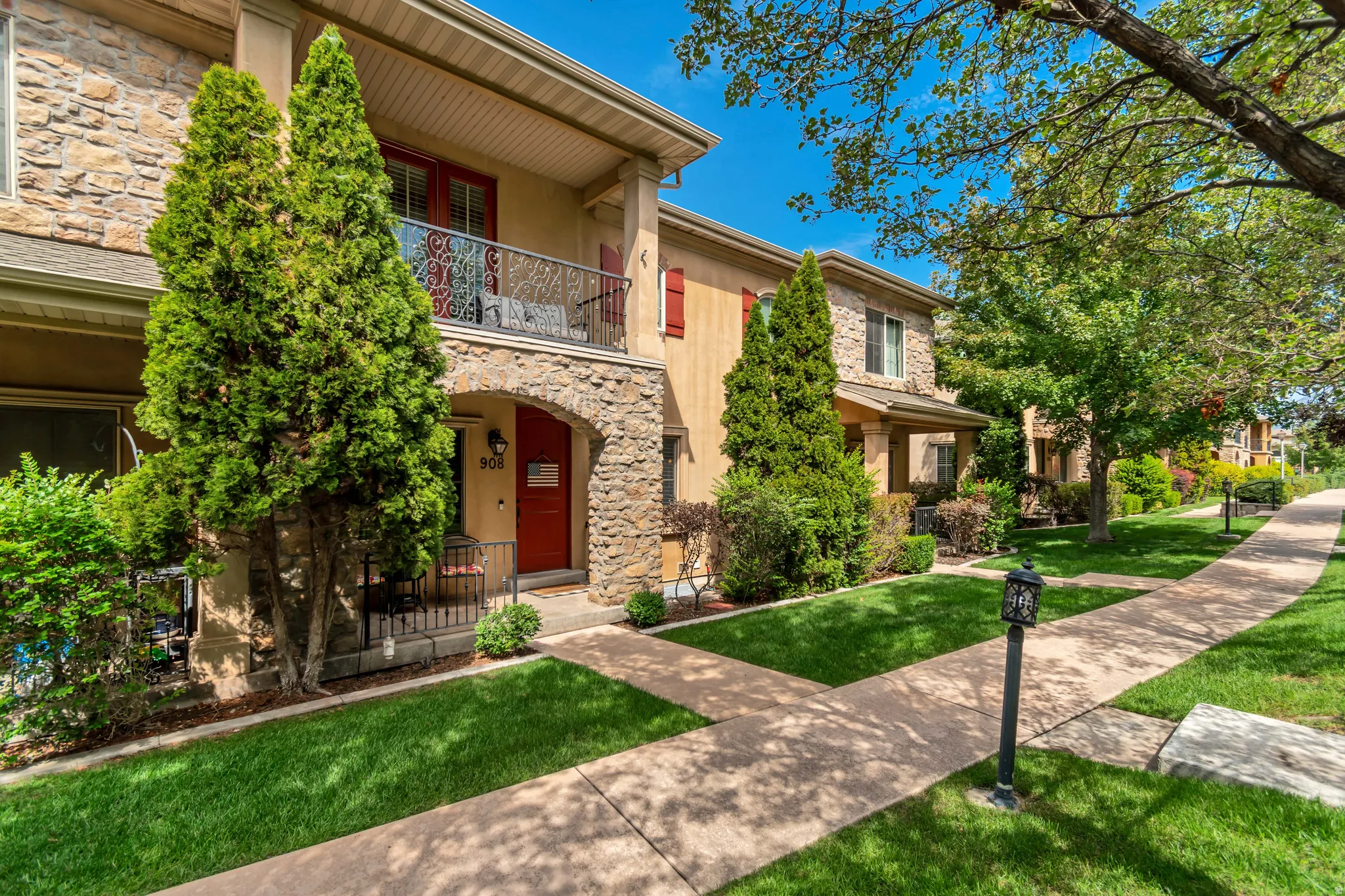 Stone and stucco exterior with a covered entry, private balcony, and decorative wrought iron railing