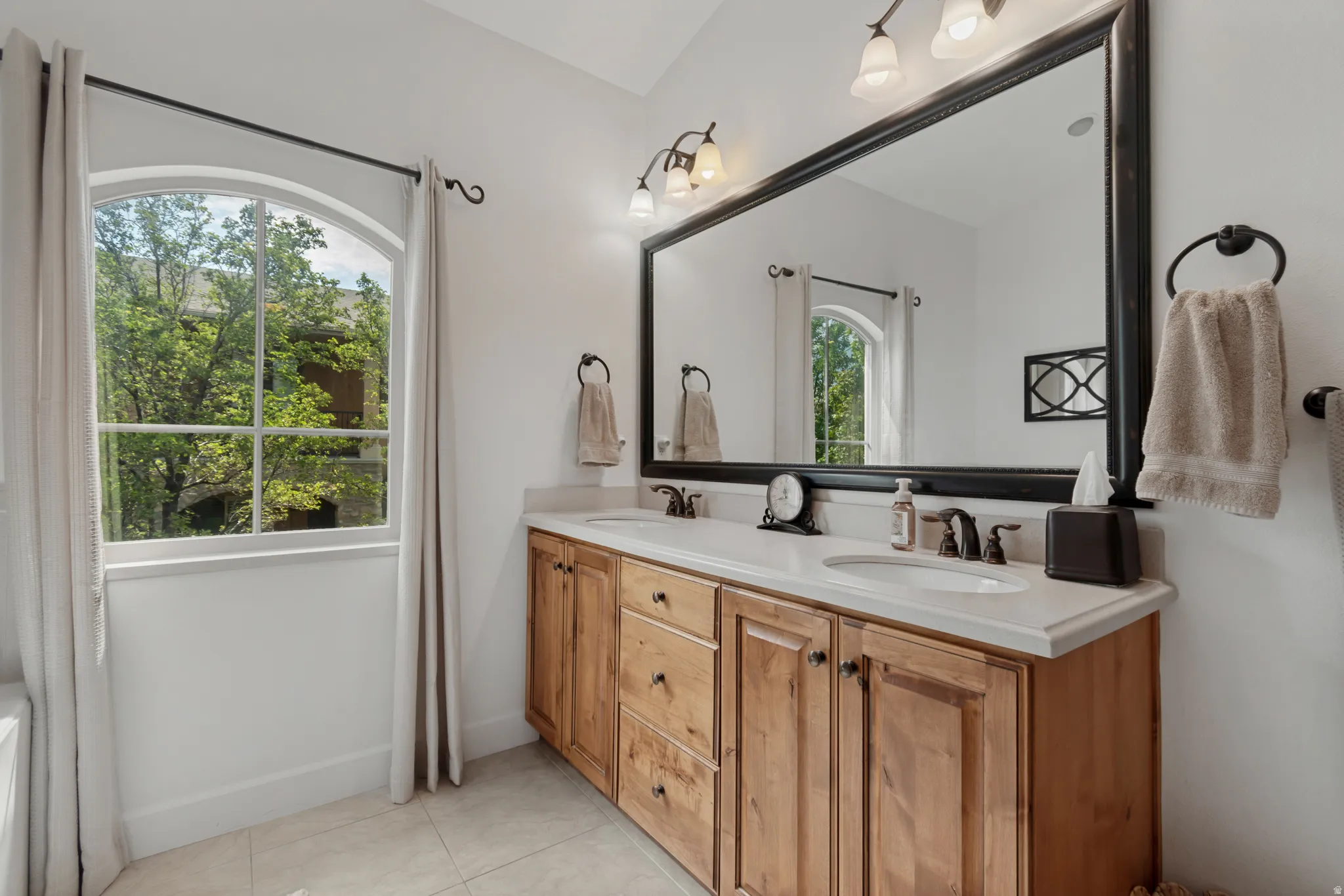 Double vanity with light wood cabinetry, dual undermount sinks, and stone countertops