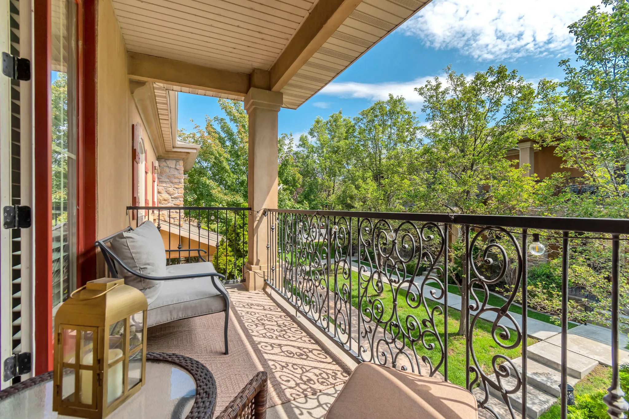 Balcony with decorative wrought iron railing, architectural columns, and wood-paneled ceiling