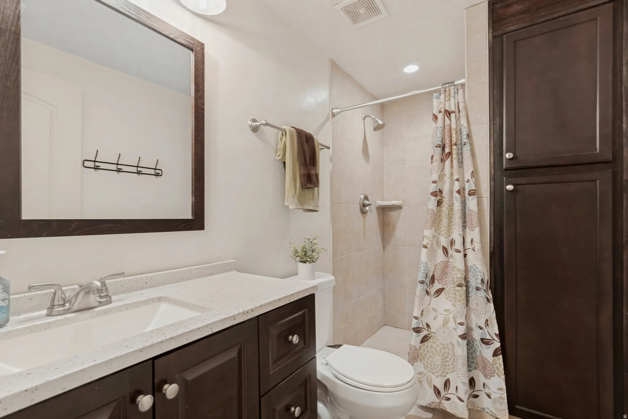 Dark wood-finish vanity with an integrated sink, light-toned countertop, and chrome fixtures