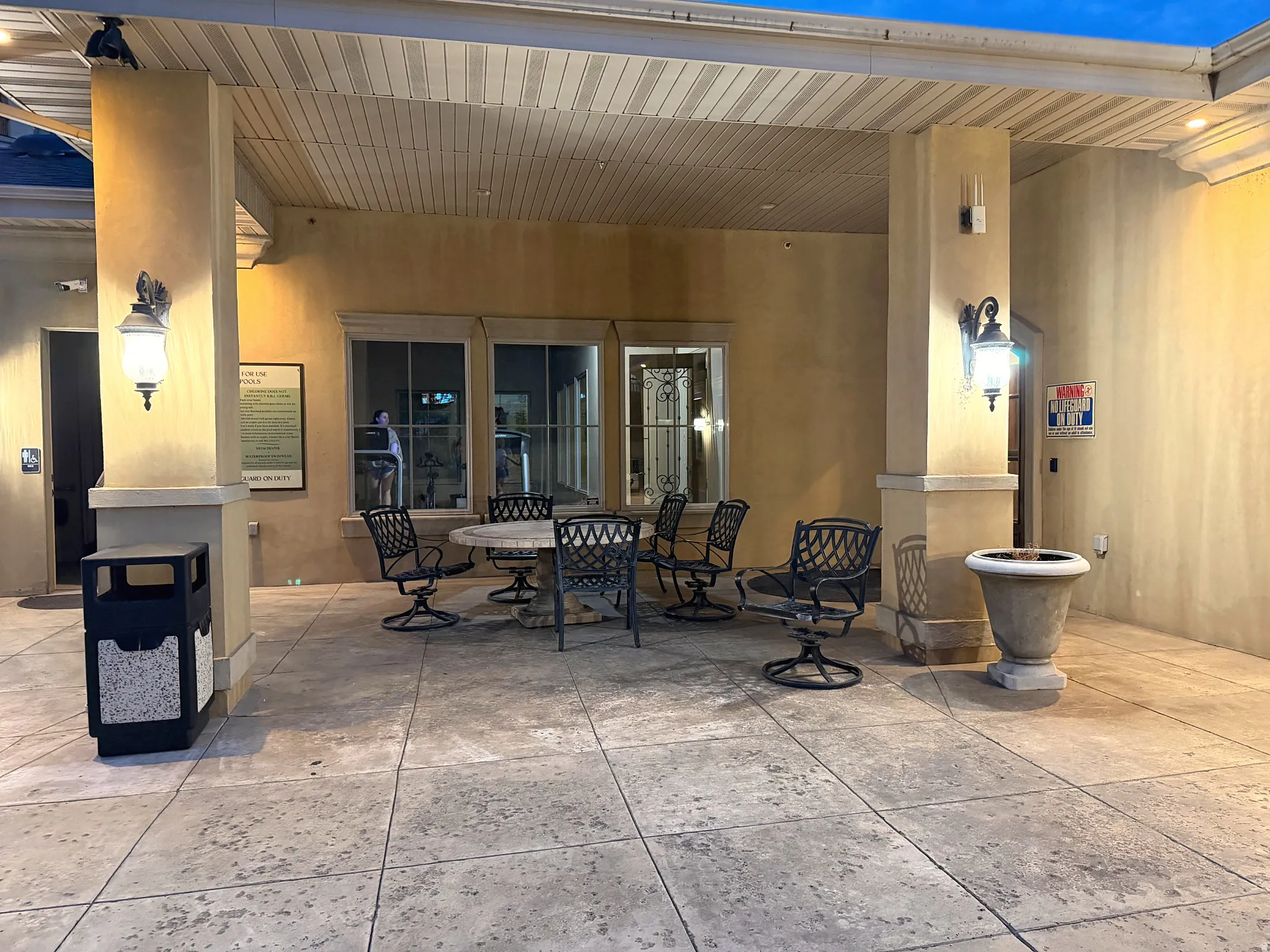 Clubhouse covered patio with stamped concrete flooring, stucco exterior, and decorative sconce lighting