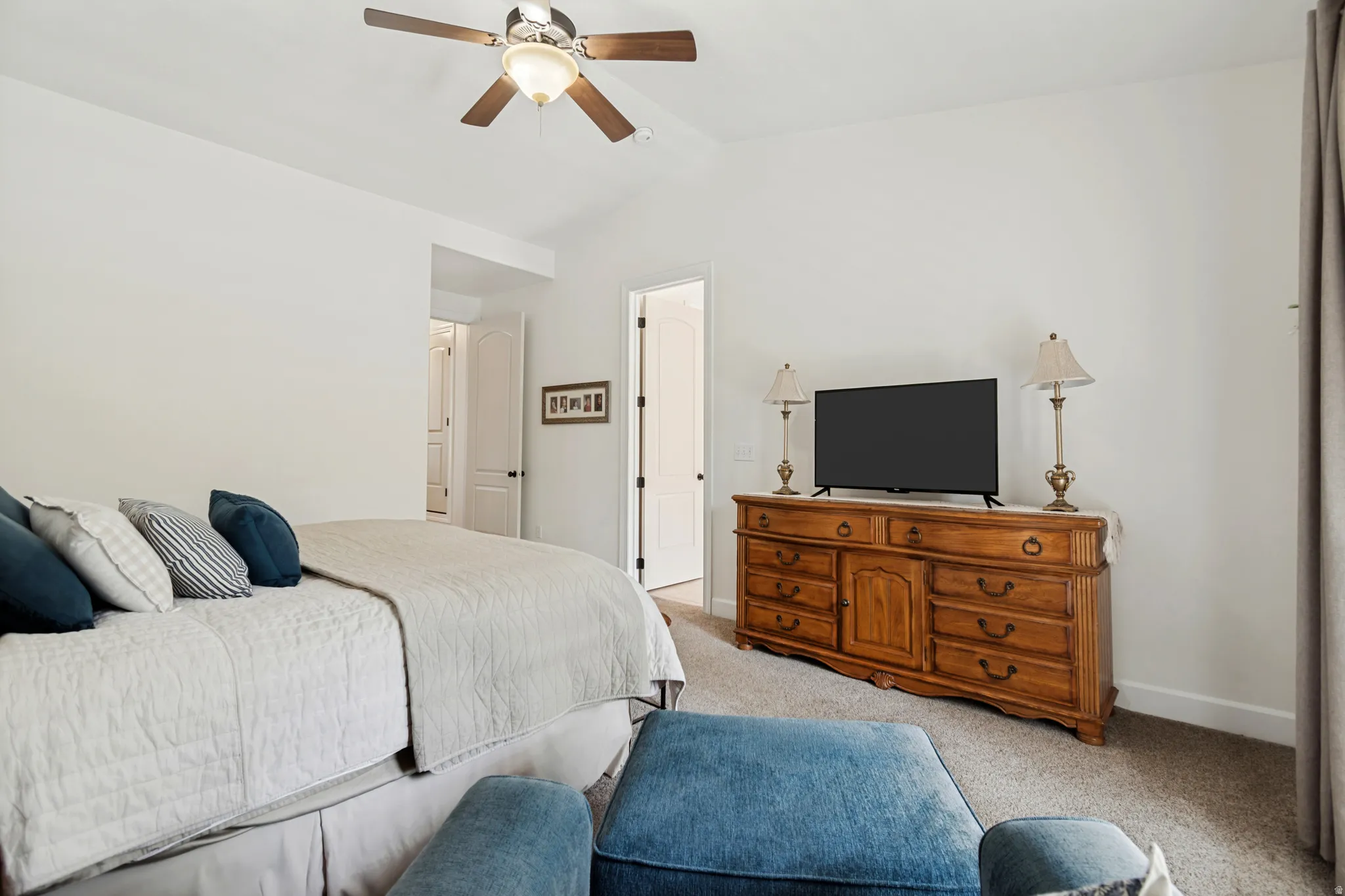 Vaulted ceiling, ceiling fan, white paneled doors, carpeted flooring, and neutral wall tones