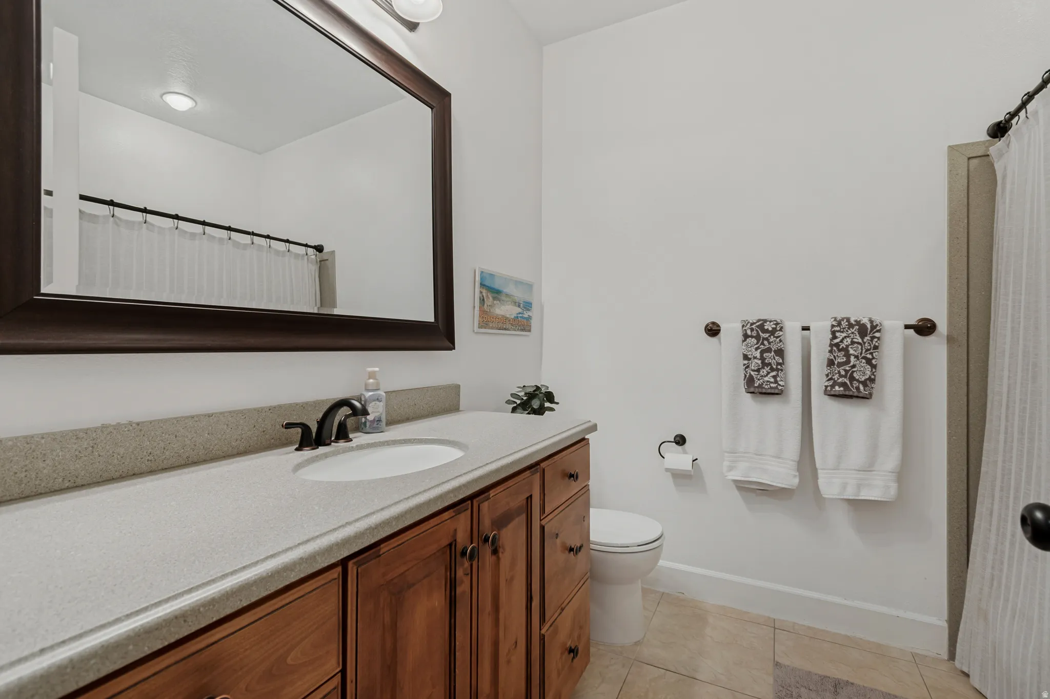Wood-finish vanity with an integrated sink, broad countertop, and bronze-finish faucet