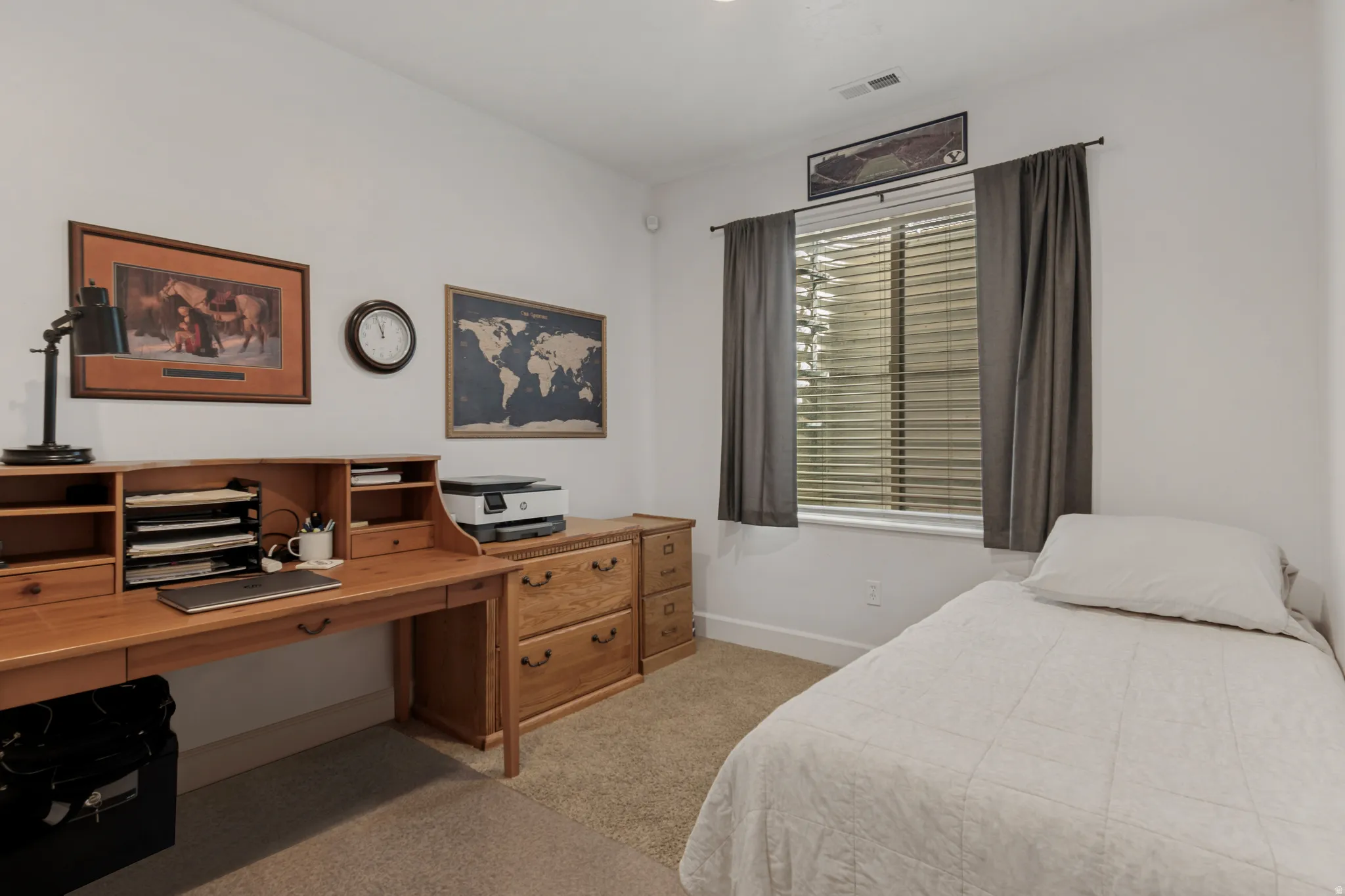 Neutral wall paint, carpet flooring, a window with blinds, and drapery rods