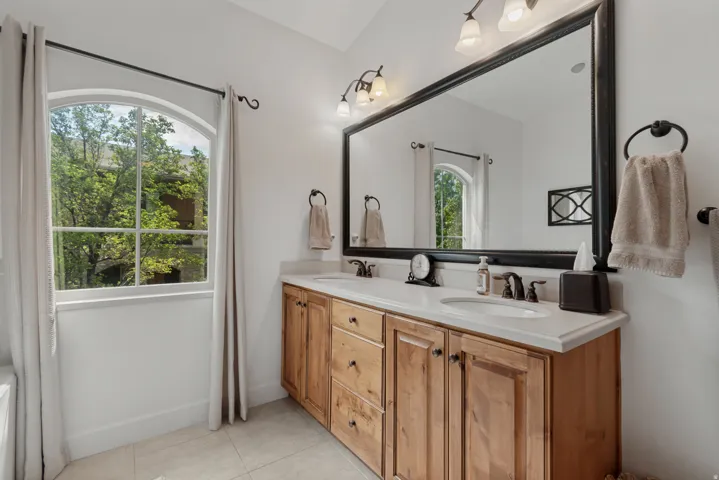 Double vanity with light wood cabinetry, dual undermount sinks, and stone countertops