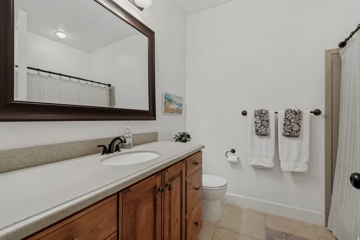 Wood-finish vanity with an integrated sink, broad countertop, and bronze-finish faucet