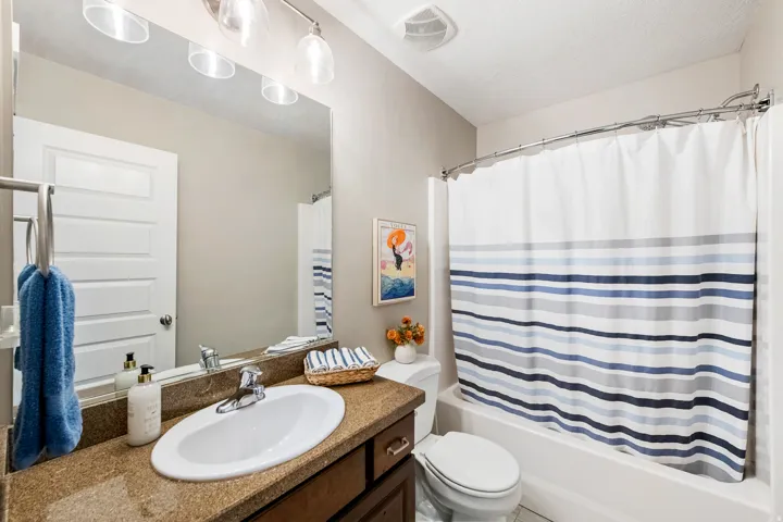 Full bathroom featuring a single vanity with an integrated sink, a built-in bathtub with shower, and overhead lighting