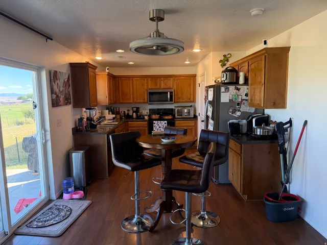 Wood-finish flooring throughout, wood cabinetry with dark countertops, stainless steel appliances, and a sliding glass door to exterior