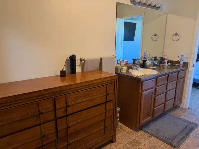 Bathroom vanity with an integrated sink and light wood-finish cabinetry, set against a large wall mirror