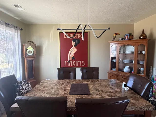 Recessed lighting and a modern linear chandelier illuminate the dining space