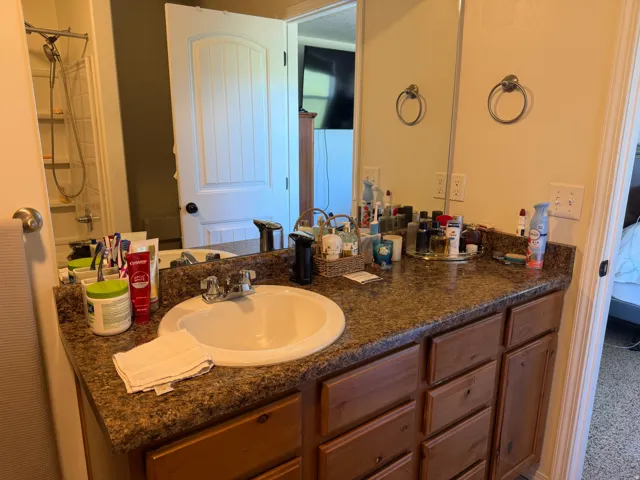 Vanity with a built-in sink, wood-finish cabinetry, and a full-width mirror