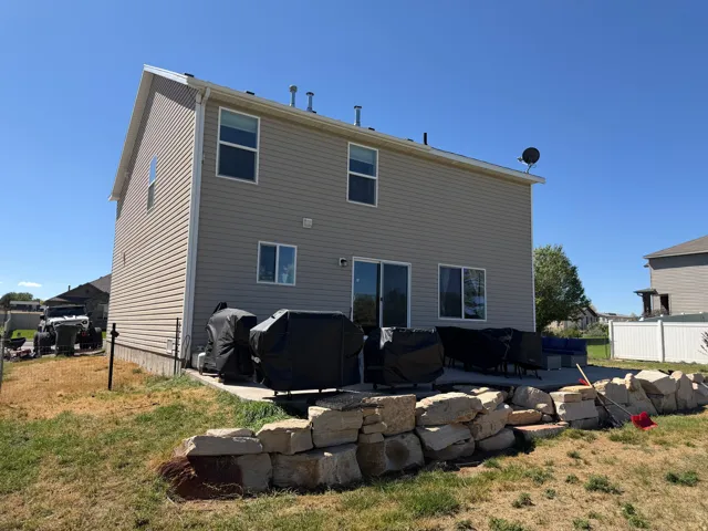 Rear exterior with horizontal siding, a ground-level concrete patio, and a stone retaining wall