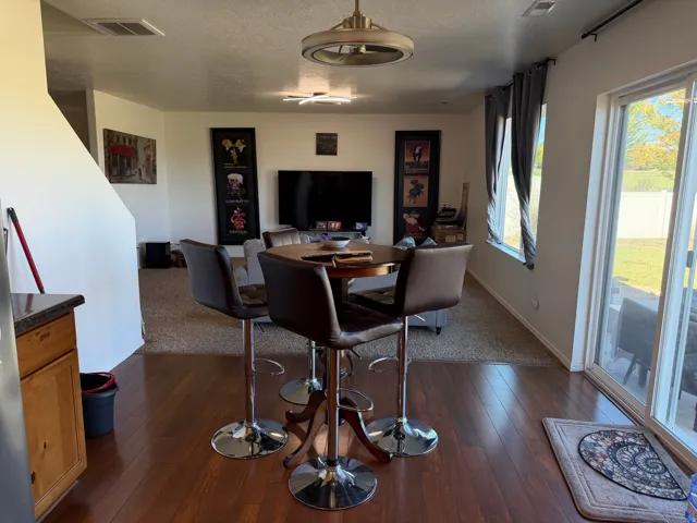Open-concept interior featuring wood-finish flooring, a sliding glass door to exterior, and a built-in kitchen cabinet with a dark countertop
