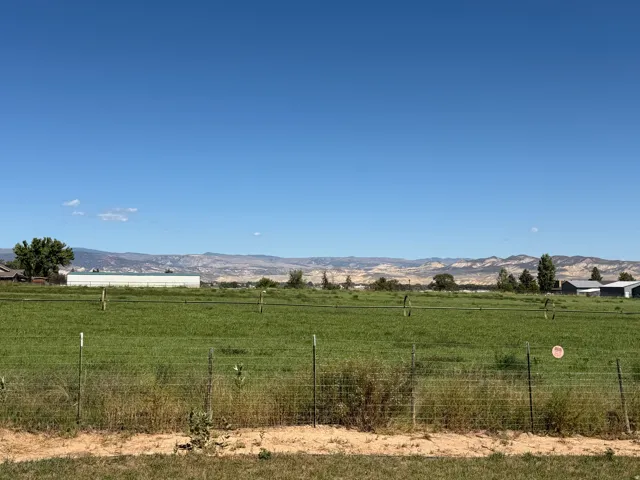 Expansive green field with wire fencing and distant mountain range