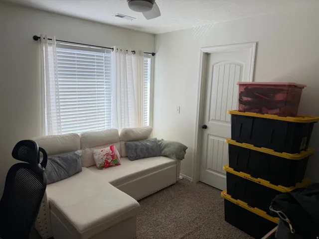 Ceiling fan, white interior door, window with blinds, light-colored walls, carpeted flooring