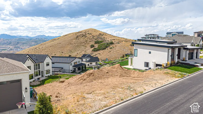 Unfinished lot featuring a paved roadway and surrounding residential structures