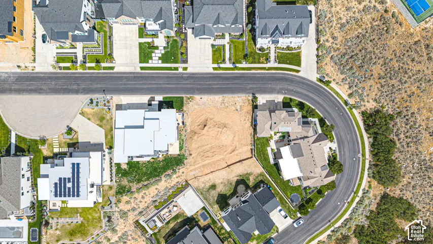Expansive vacant lot with surrounding residential properties, paved street access, and adjacent natural terrain