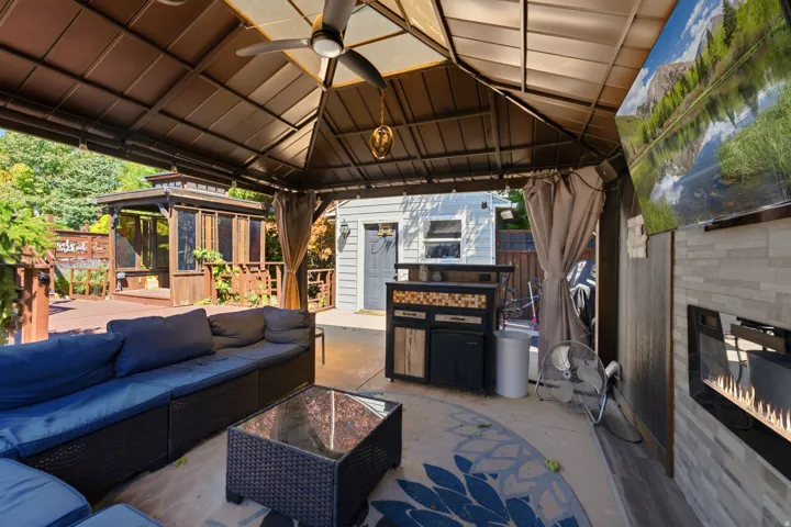 Covered patio with ceiling fan, built-in fireplace, and stone-look accent wall