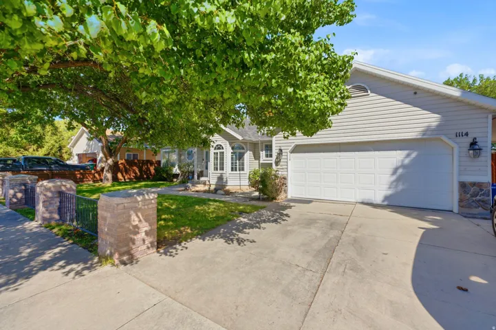 Exterior featuring light-toned siding, stone accents, a two-car garage, and a concrete driveway