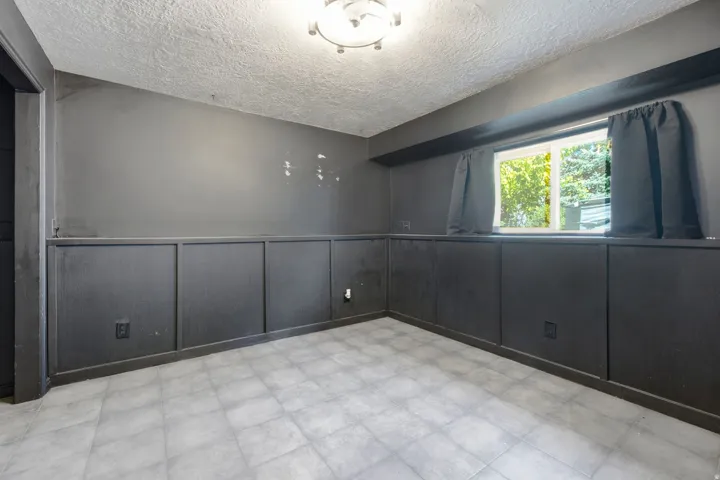 Recessed window, textured ceiling, tile flooring, and wainscoting