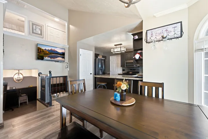 Wood-finish flooring throughout, vaulted ceiling, and dark wood cabinetry in the kitchen