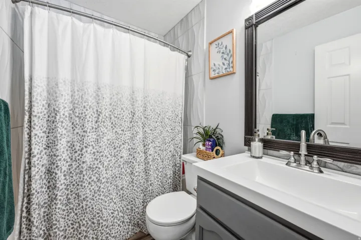 Bathroom featuring a vanity with an integrated sink, a large framed mirror, and a toilet