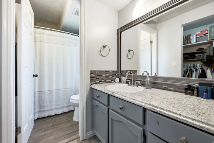Bathroom featuring a single vanity with gray cabinetry, a light-toned countertop, and a rectangular undermount sink