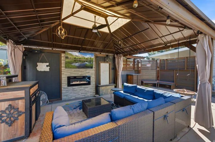 Covered outdoor living space featuring a built-in fireplace, a ceiling fan, and string lighting