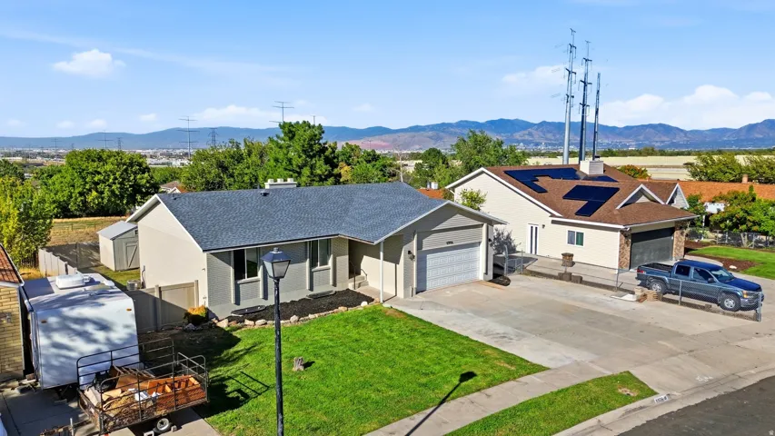 Exterior featuring a gray asphalt shingle roof, attached garage, well-maintained lawn, and a storage shed