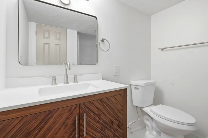 Modern vanity with wood-finish cabinetry, integrated sink, and white countertop