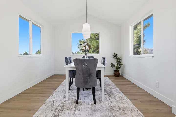 Vaulted ceiling, wood-finish flooring, multiple windows, recessed lighting, and a contemporary pendant light fixture