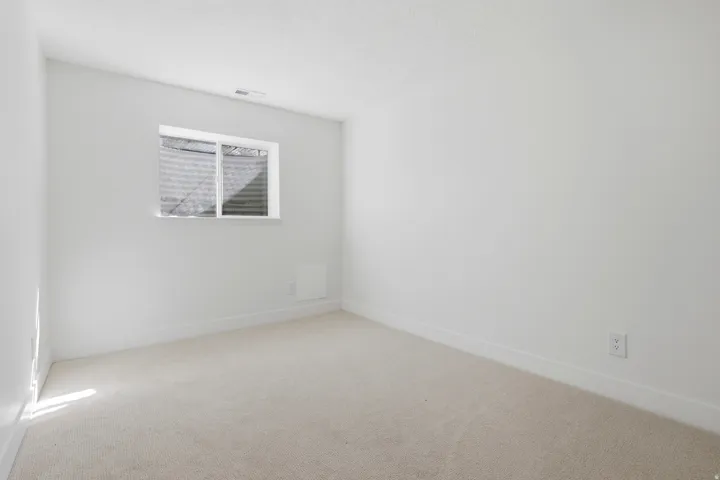 Carpeted flooring, white painted walls, and a single window with a white frame