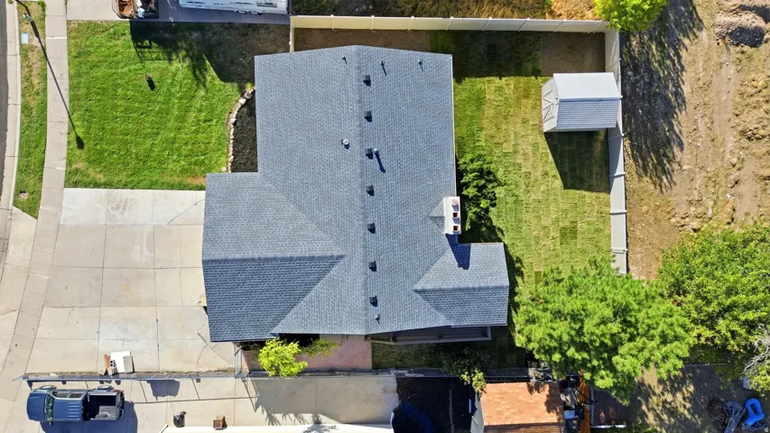 Asphalt shingle roof with multiple vents, a chimney, and a concrete driveway